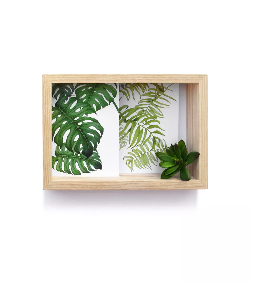 Bilder- und Kartenrahmen aus Holz mit einer dekorativen grünen Blüte in der Ecke und Karten auf denen Farne zu sehen sind.